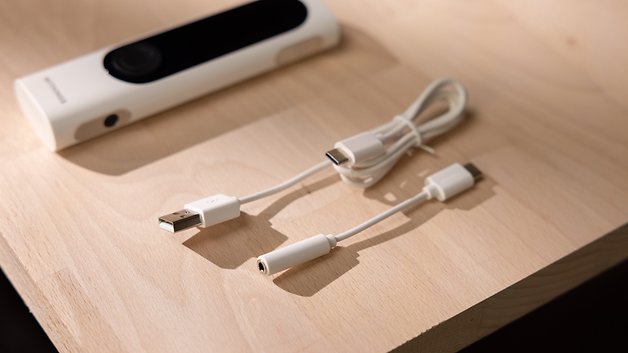 A Withings BeamO device and two white cables on a wooden surface.