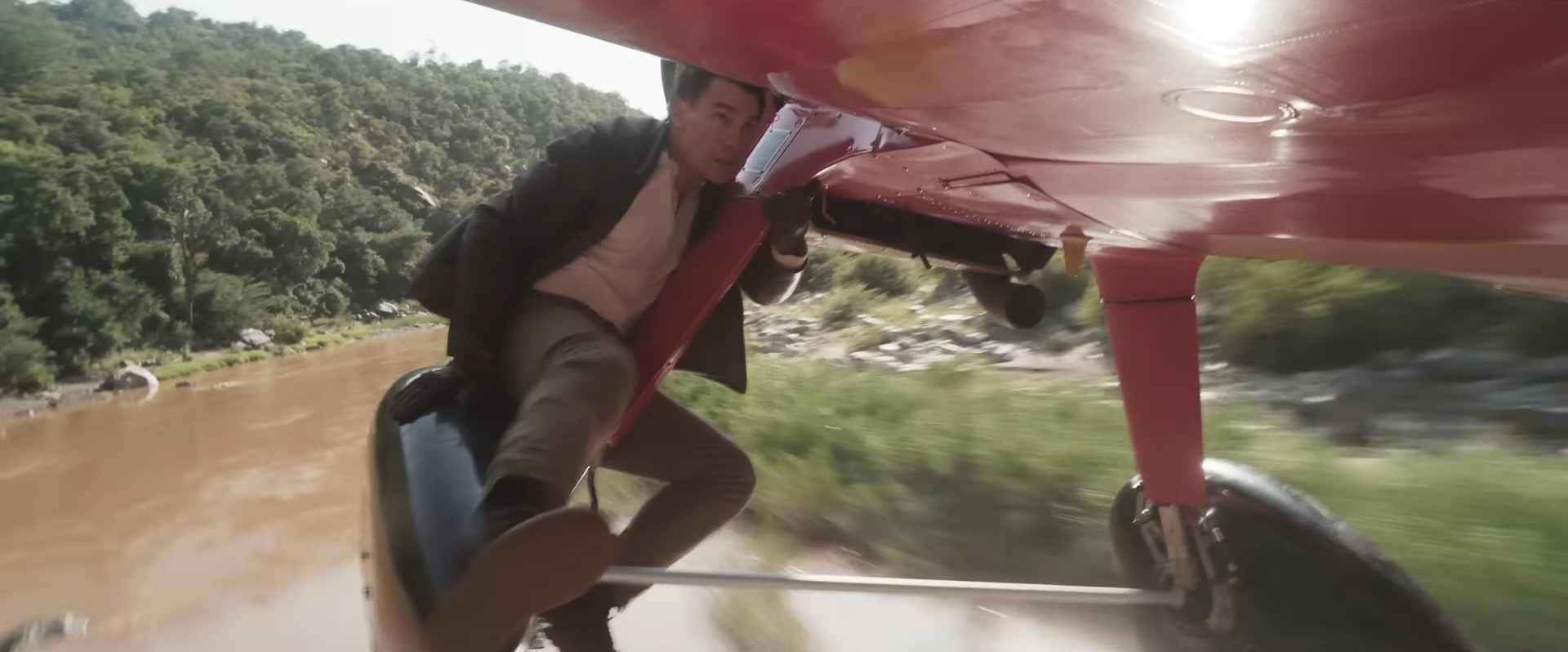 Tom Cruise hanging from a red plane in 