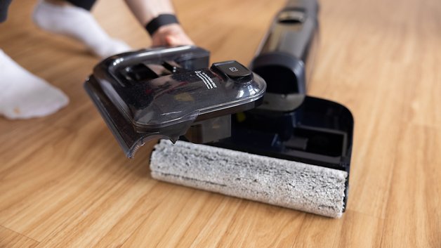 The person holds a removable part of Floor Tineco One S7 Planer on a wooden floor