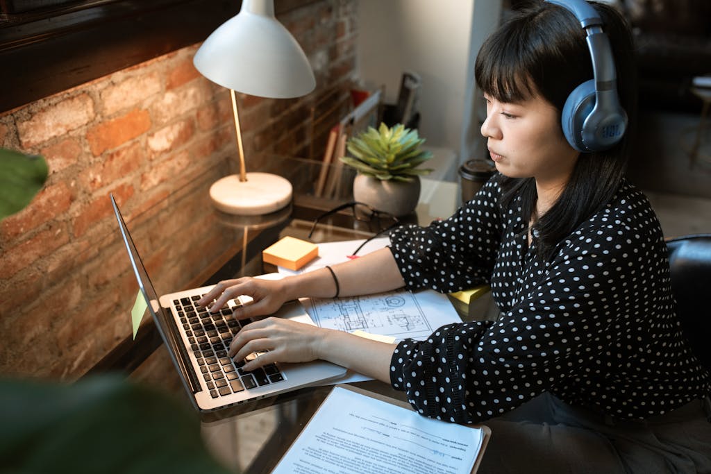 Why Bloggers Should Care About Make Money Online in 2026 2 Focused woman wearing headphones, working on a laptop in a cozy home office setup with natural light.